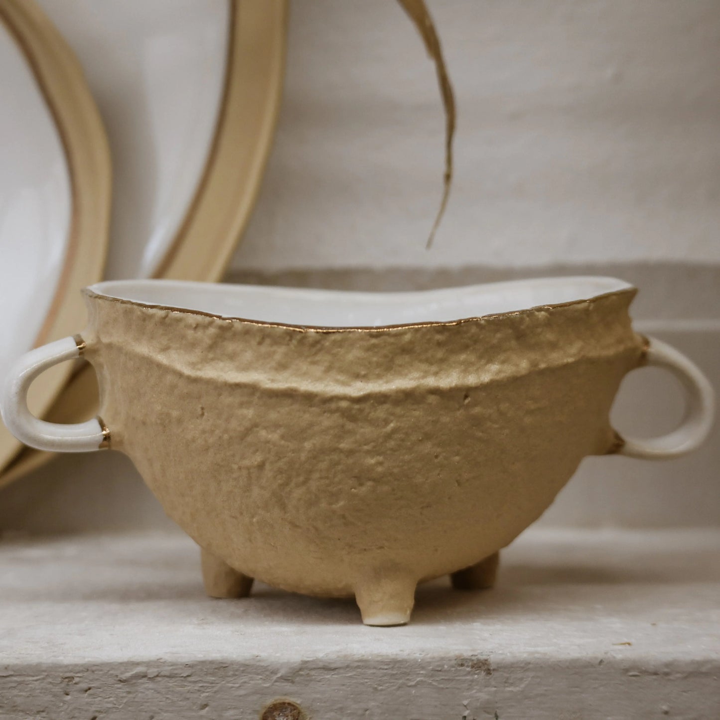 Nosse Ubuntu Bowl Aura Gold on display shelf – sculptural modern ceramic design