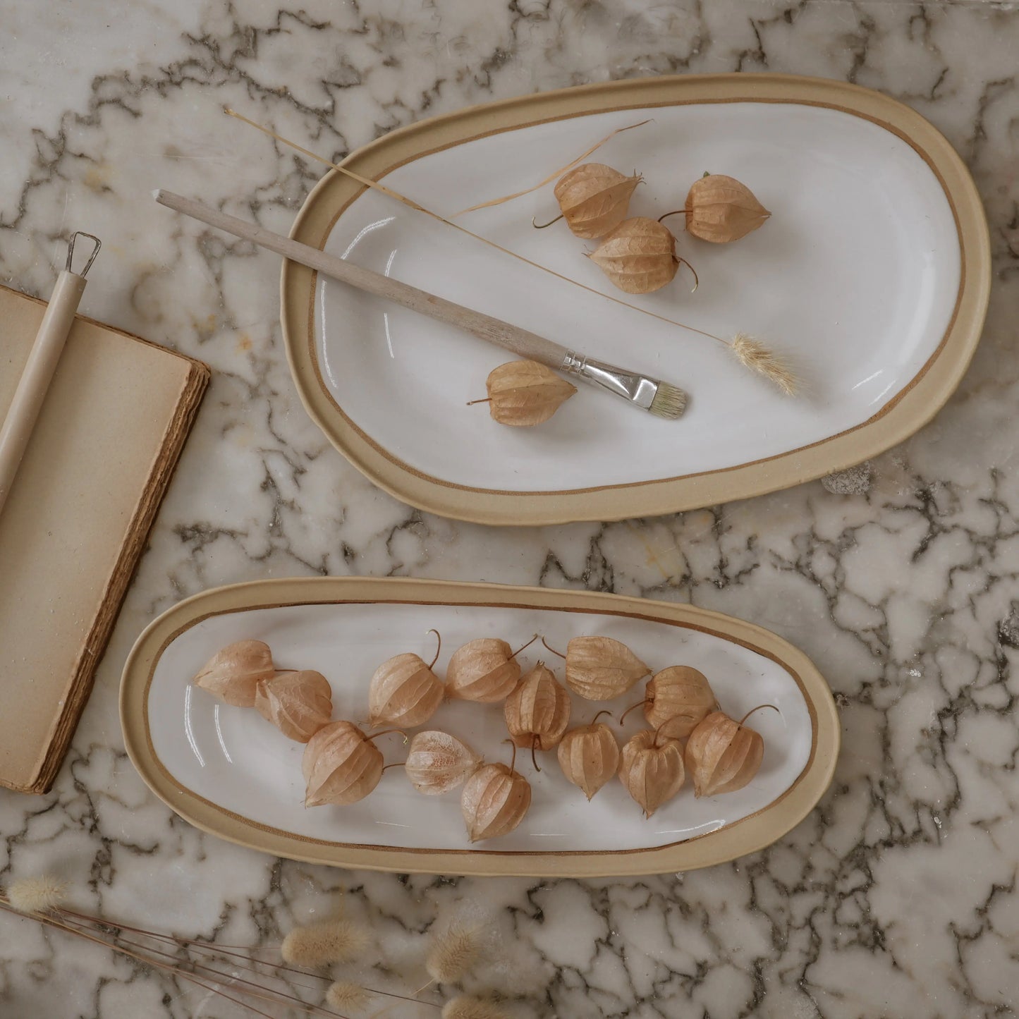 Nosse modern ceramic platters on marble surface in beige and white tones, Portuguese contemporary tableware.