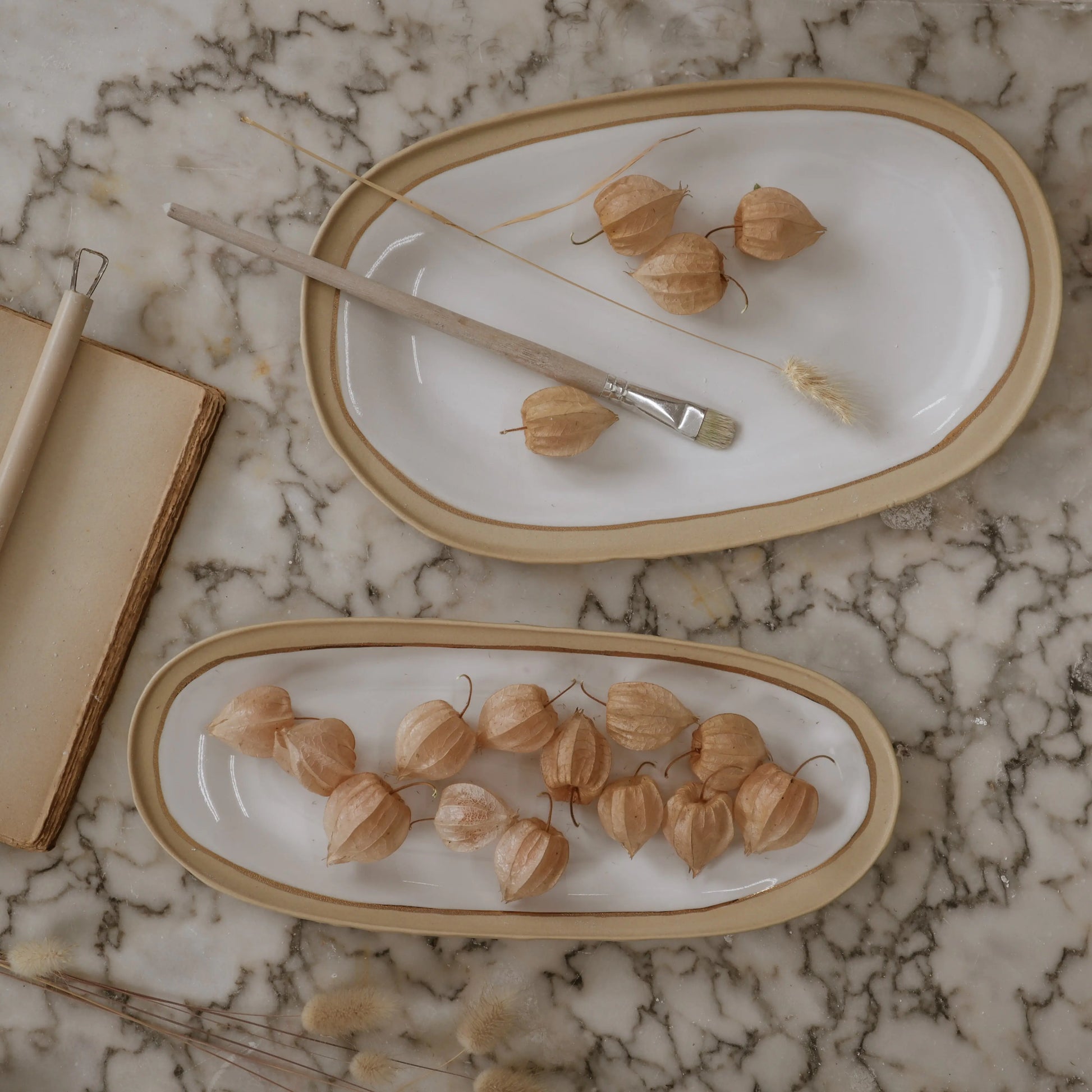 Nosse modern ceramic platters on marble surface in beige and white tones, Portuguese contemporary tableware.